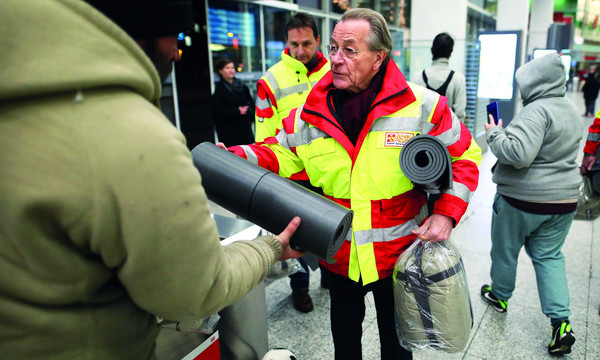 ASB-Präsident Franz Müntefring überreicht Wohnungslosem Schlafsack und Isomatte.